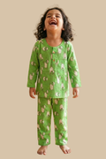 Child wearing green pajamas with animal pattern on a beige background
