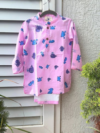 Pink shirt with blue whale patterns hanging on a white wall